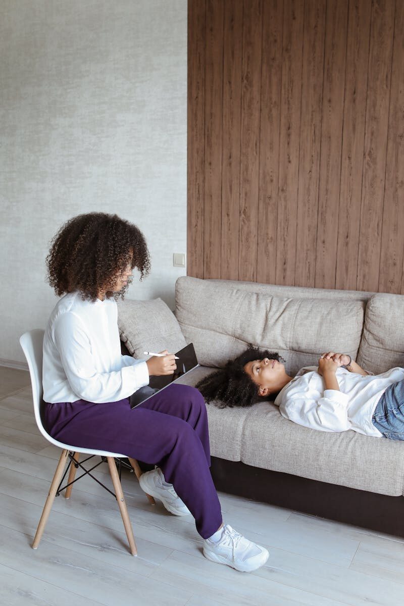 A therapy session featuring two women, one as therapist, discussing in a cozy, modern setting.